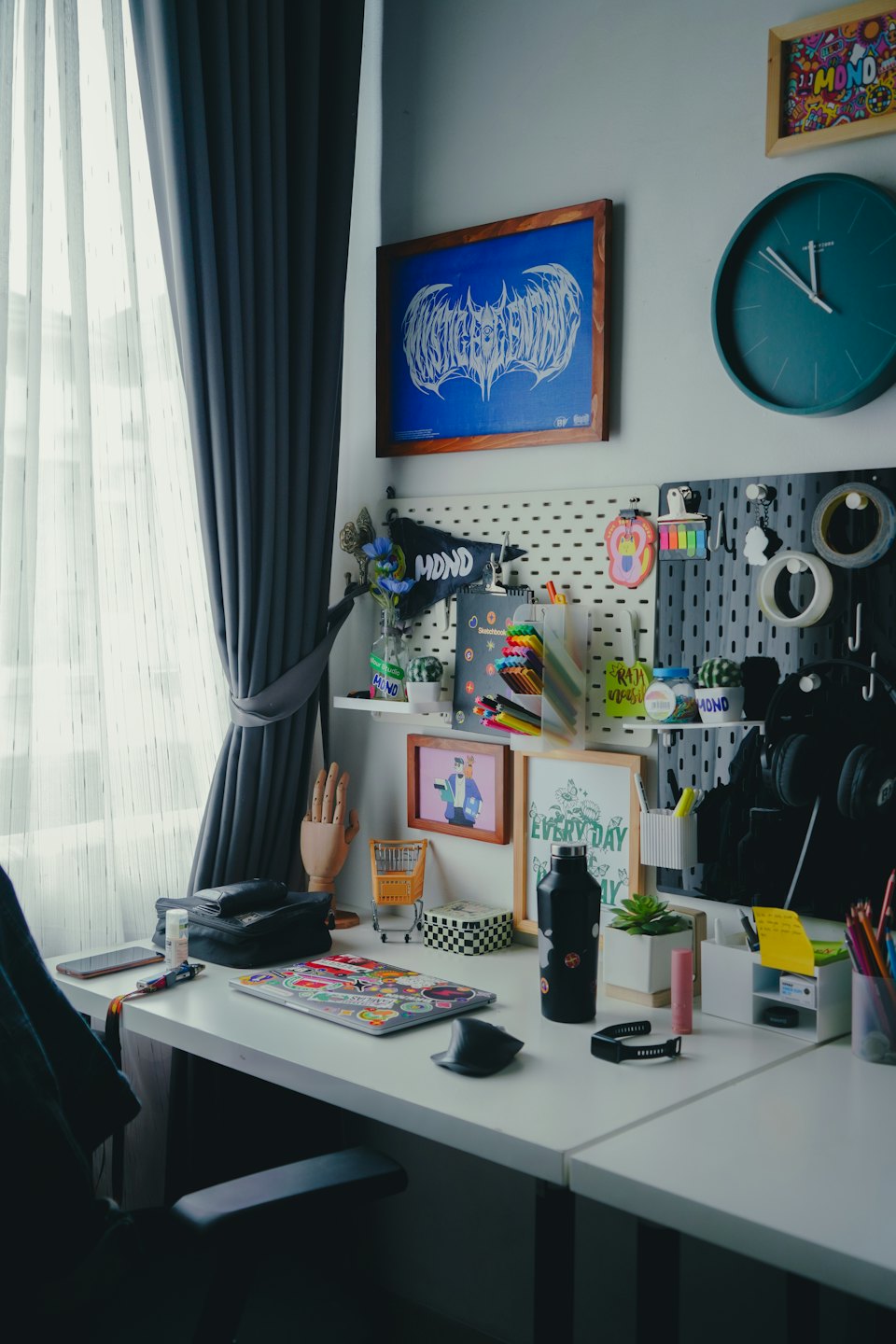 Home office desk with laptop, headphones, and art supplies.