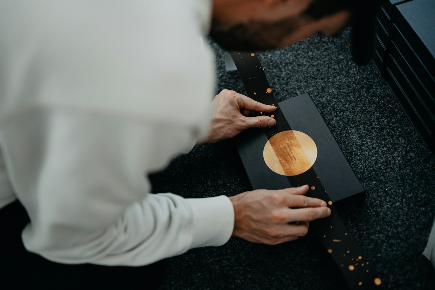 Hands arranging a decorative black box with gold details.