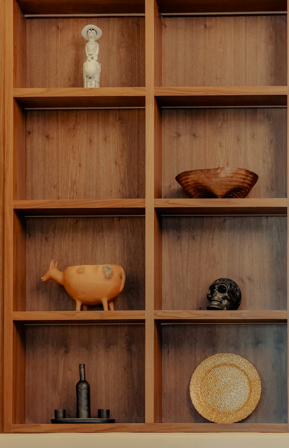 Natural wood shelving unit displaying curated decorative ornaments and ceramics.